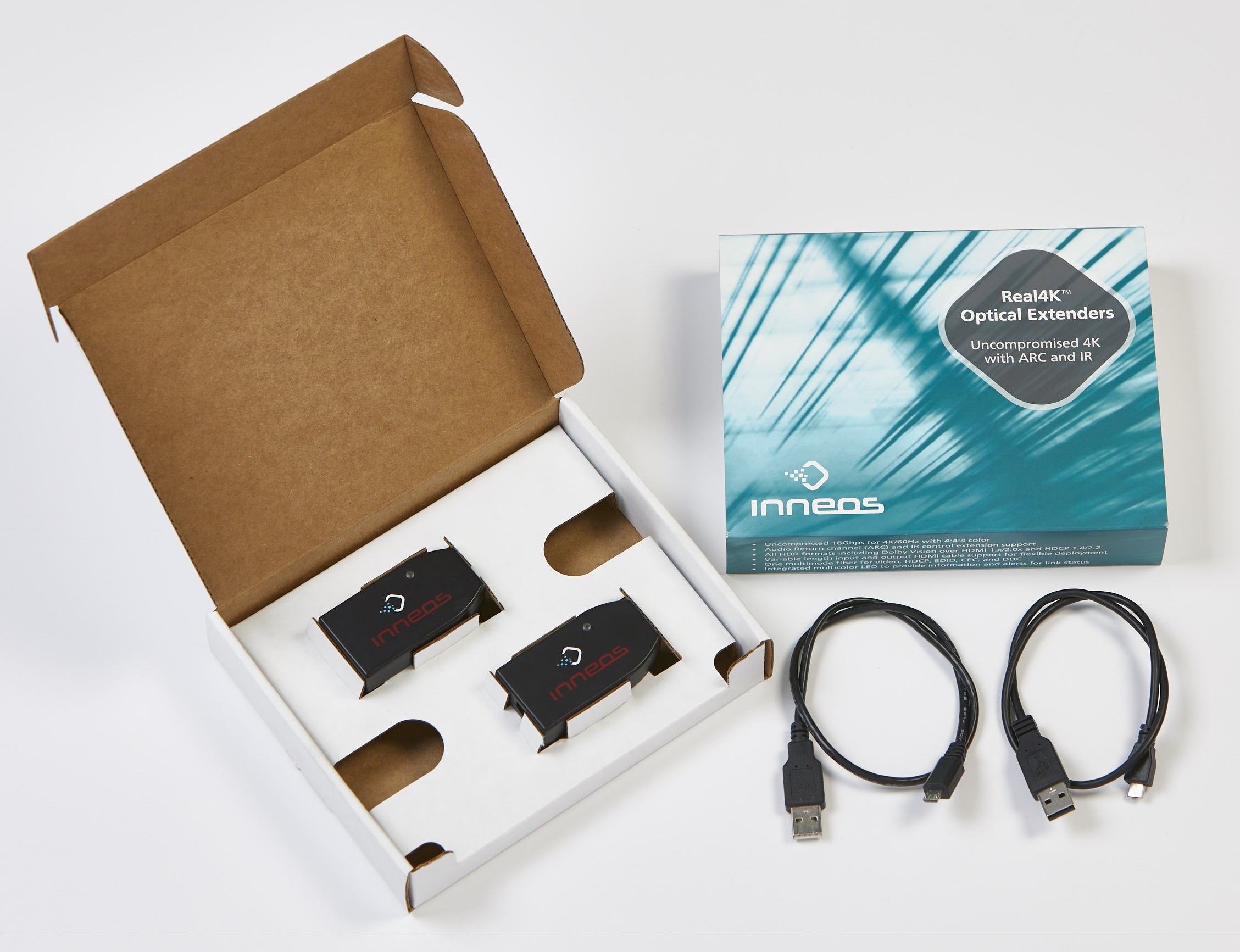 Two black extenders in a white cardboard box with a blue box and two cable coils next to it on a white background.