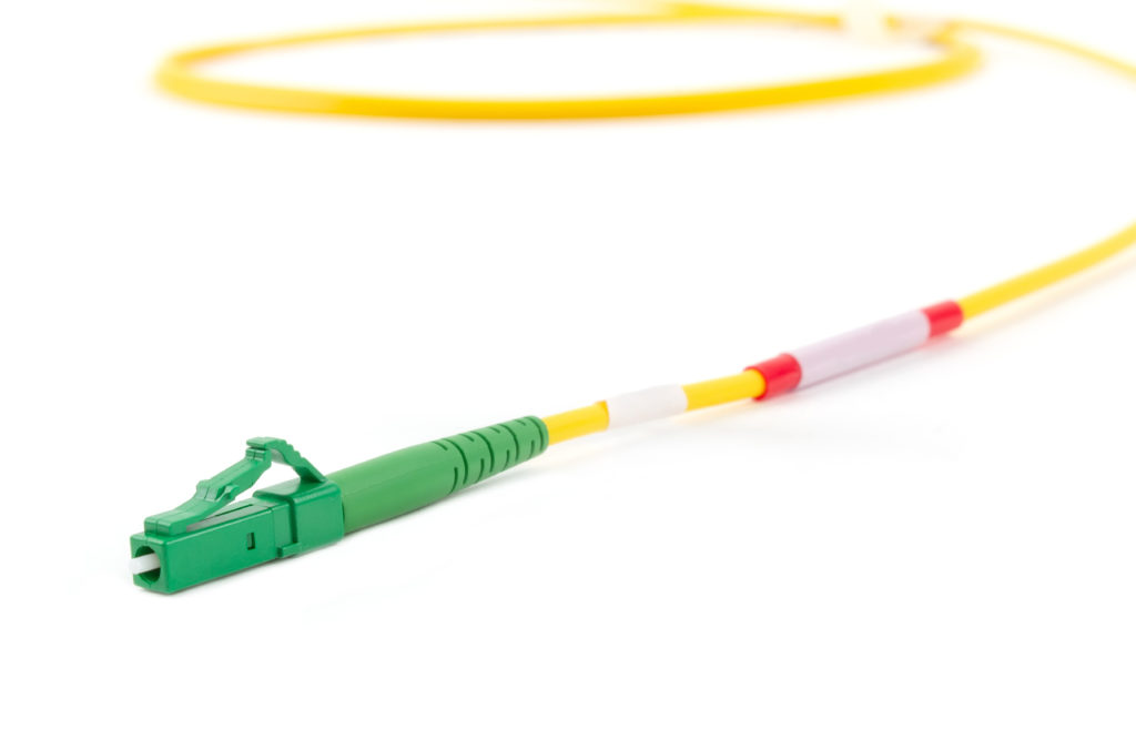 Inneos | Multimode vs. Single Mode Fiber: Does It Matter? Single mode fiber optic cable with green LC connector isolated on white background.