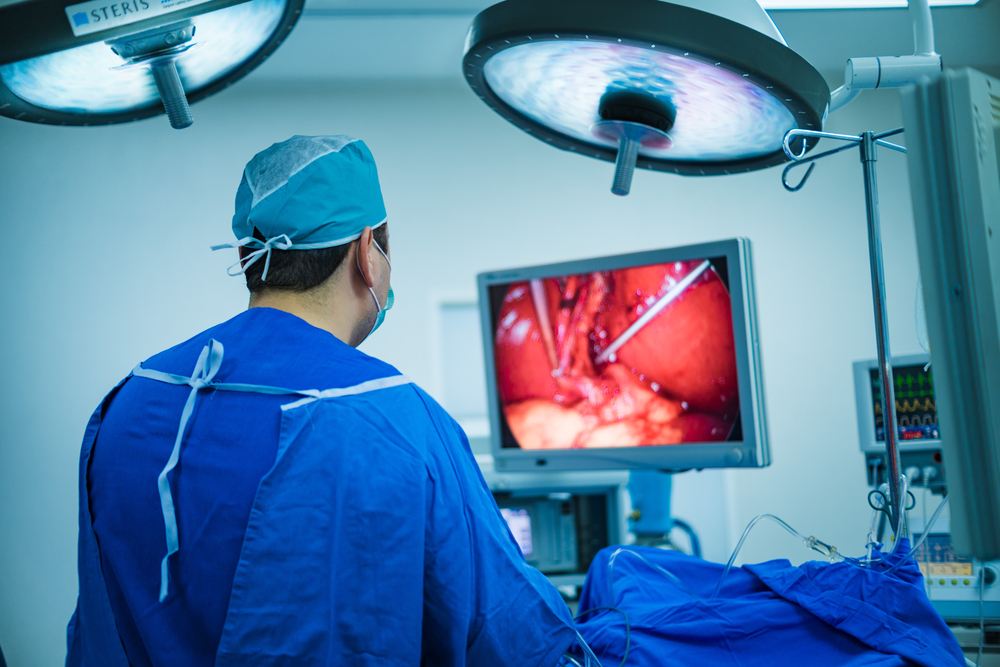 Surgeon in an operating room, standing in front of a screen. 