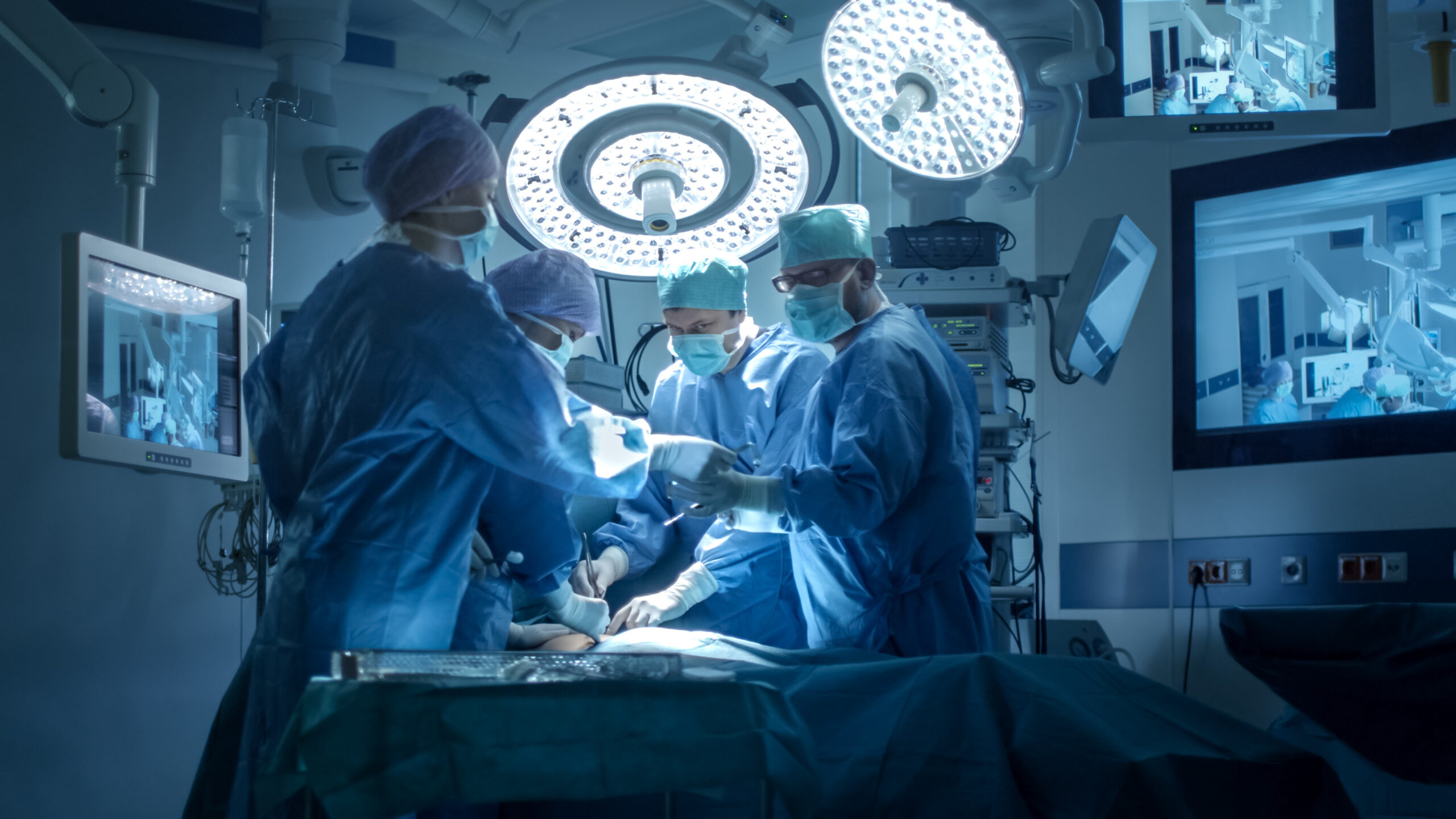 Inneos | What is Wavelength Division Multiplexing and Why Should You Care About It? Four surgeons in an operating room with surgical screens in the background.